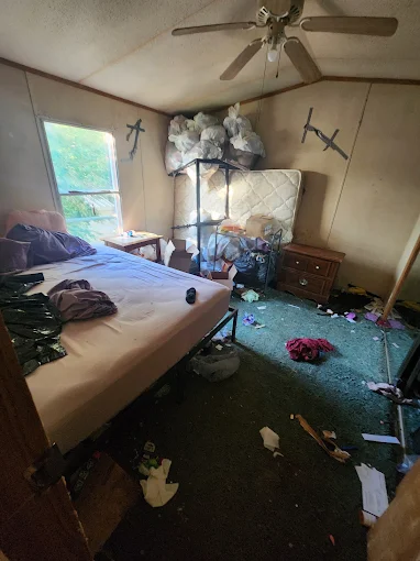 Trashed bedroom with debris and trash bags covering the floor — eviction cleanout
