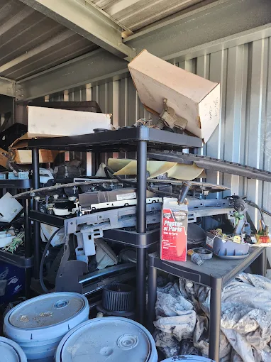 Packed storage container with metal shelving, drums and miscellaneous items