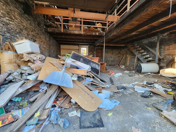 Interior building cleanout before — debris and boards covering the floor