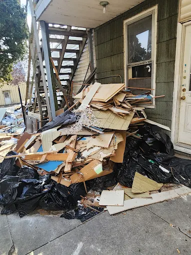 Large pile of demolition debris and trash bags outside a house before haul-away