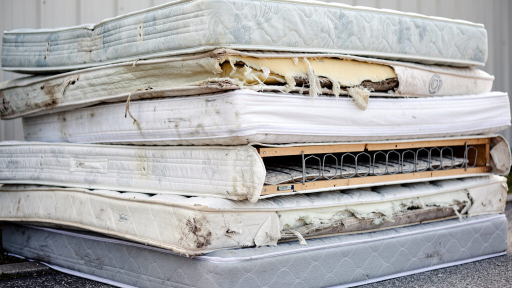Mattress being carefully carried down a staircase by two crew members